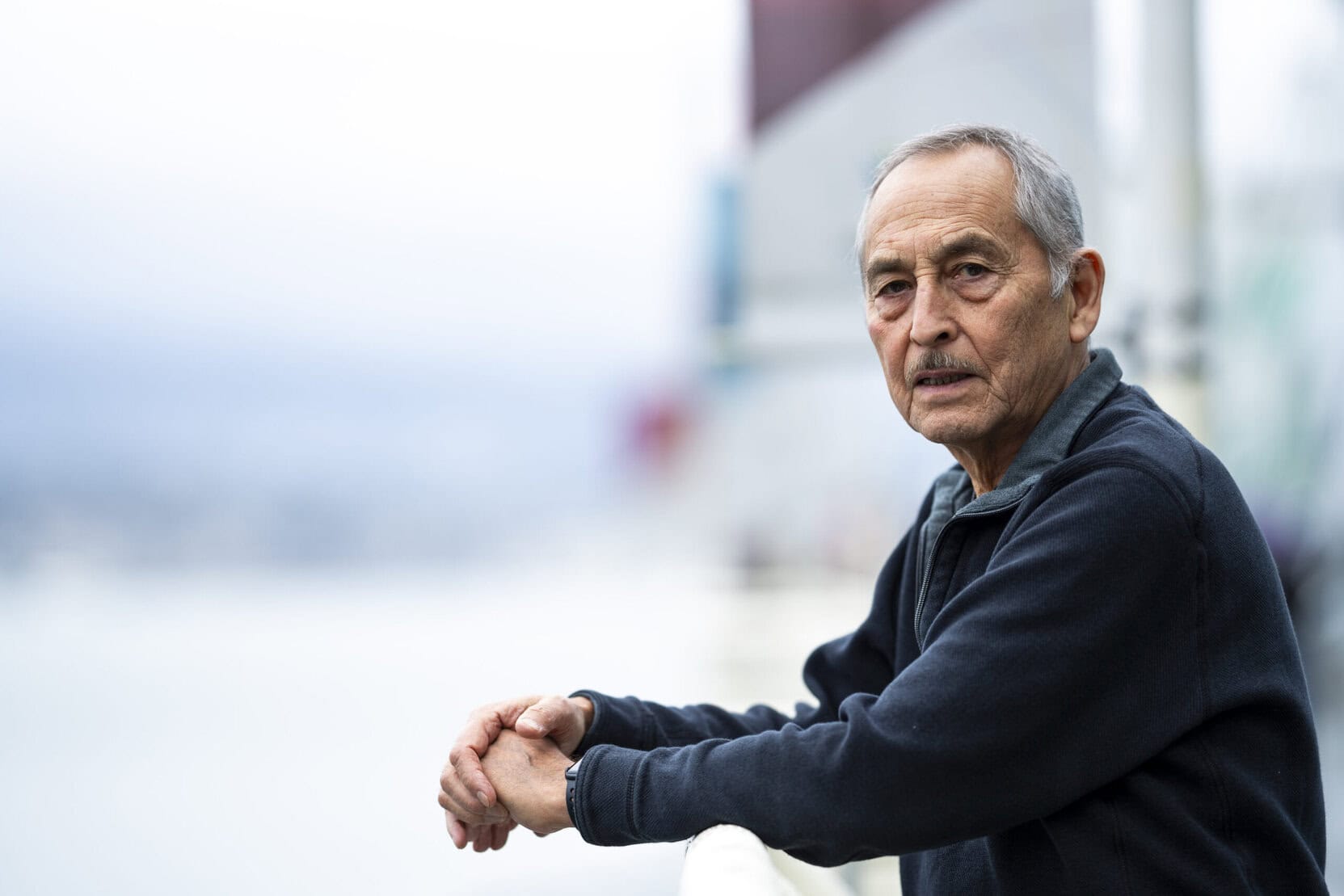 Tahltan Elder, Allen Edzerza, poses for a photo and leans over a railing at the Vancouver Convention Centre. He's wearing a dark sweater.