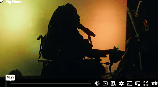 The vimeo cover of our documentary, featuring a black woman with dreadlocks, in an electric wheelchair silhouetted against a colourful background