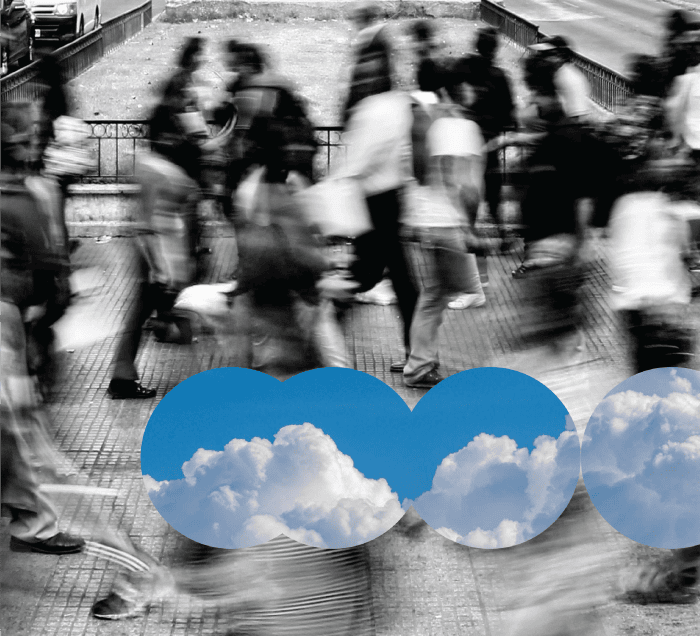 A blurred black and white photo of people walking on a street, with circular cutouts revealing bright blue sky and white clouds underneath.