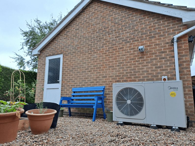 A heat pump next to an ordinary 1980s home.