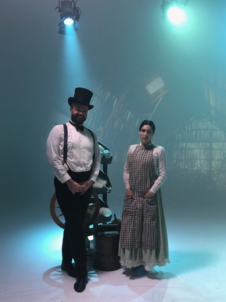 Two performers in Victorian-era costumes on fog-filled studio set with dramatic blue stage lighting, Tulsa Opera campaign