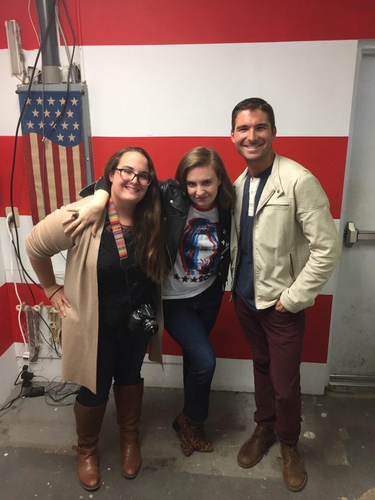 Lena Dunham, James Kicklighter and Layne Turci posing together indoors in front of American flag and red-white striped backdrop in Virginia, November 2016