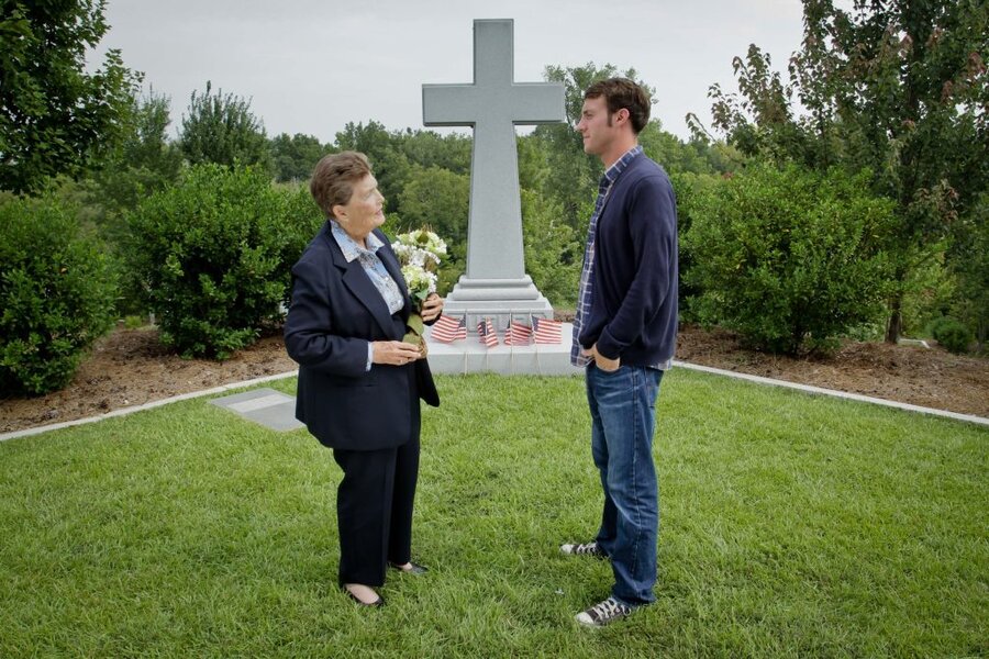 Director James Kicklighter speaks with actor beside stone cross memorial decorated with American flags in Macon, GA