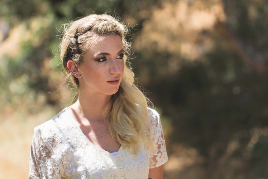 Blonde woman in white lace blouse with braided hairstyle outdoors, Branches music video production