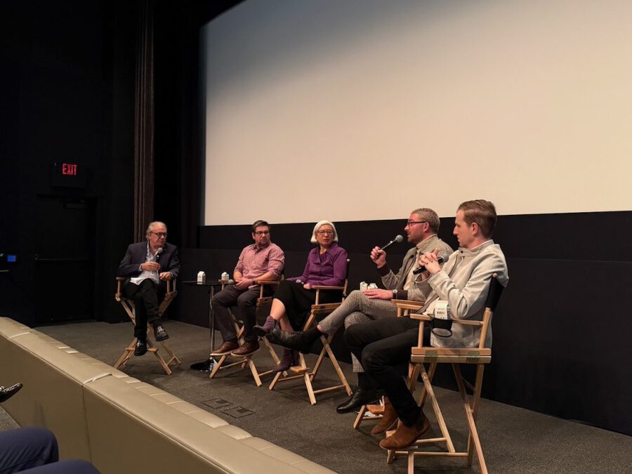 Five panelists seated on stage during a Q&A at The American Question screening in Beverly Hills, December 2024 with James ...
