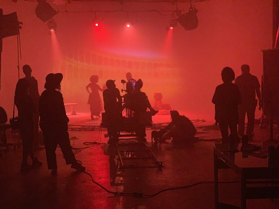 Film crew and cast on atmospheric set with red stage lighting and fog during Tulsa Opera Ad Campaign shoot