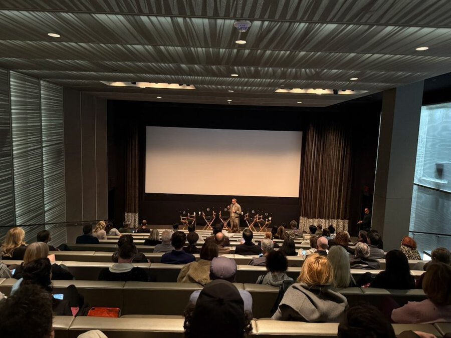 Audience members seated in a screening room watching The American Question, with a large projection screen visible at front.
