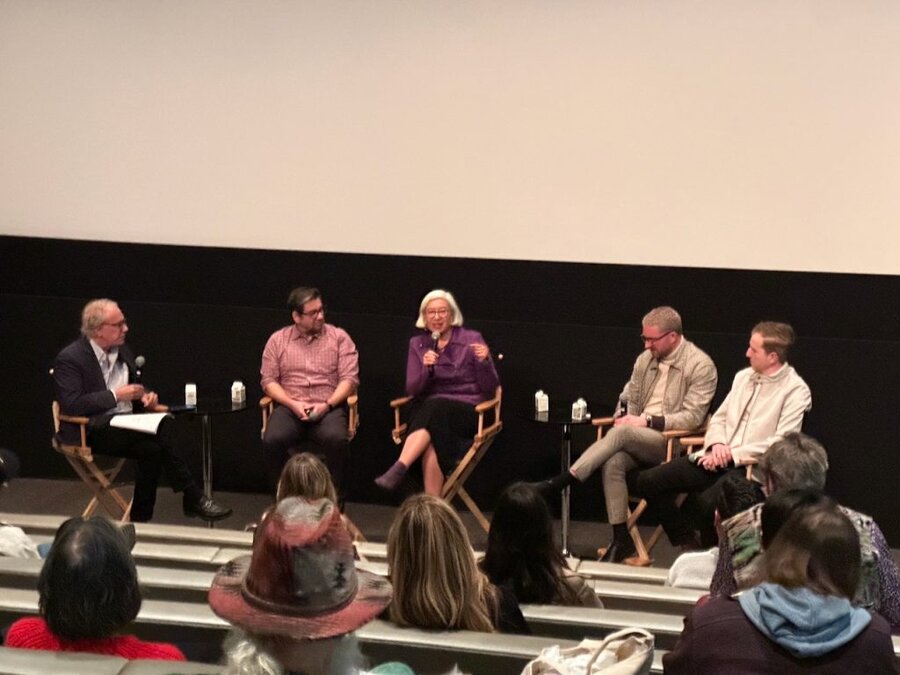 Five panelists seated on stage with moderator and audience members visible in theater setting, Beverly Hills screening