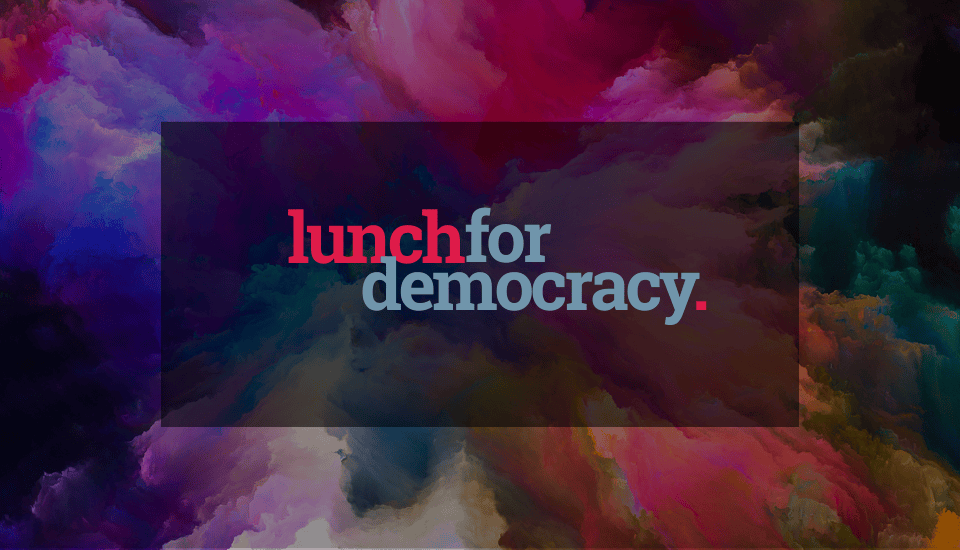 Text "lunch for democracy." in bold, colorful letters is centered on a dark transparent rectangle, set against a vibrant, swirling background of pink, purple, blue, and black abstract clouds.