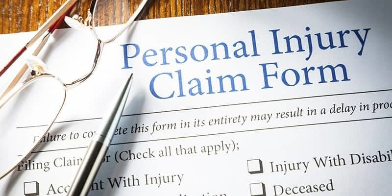 Personal Injury Claim form with pen and glasses