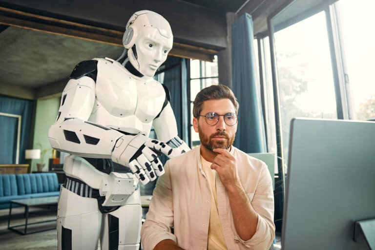 Lokale LLM im Unternehmen: Ein Roboterassistent und ein junger Geschäftsmann arbeiten gemeinsam an einem Computer in einem modernen Büro. Eine Zusammenarbeit zwischen Mensch und künstlicher Intelligenz.