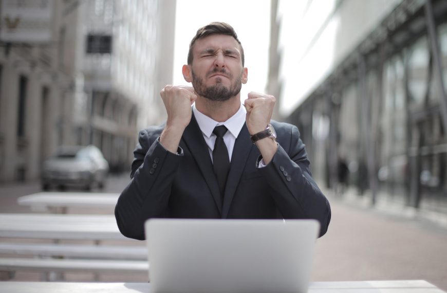 Frustrated businessman in suit clenches fists, symbolizing debt relief success or financial achievement.