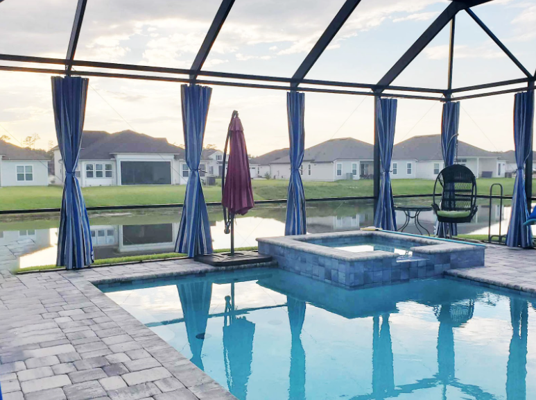 Swimming pool enclosure with privacy curtains.