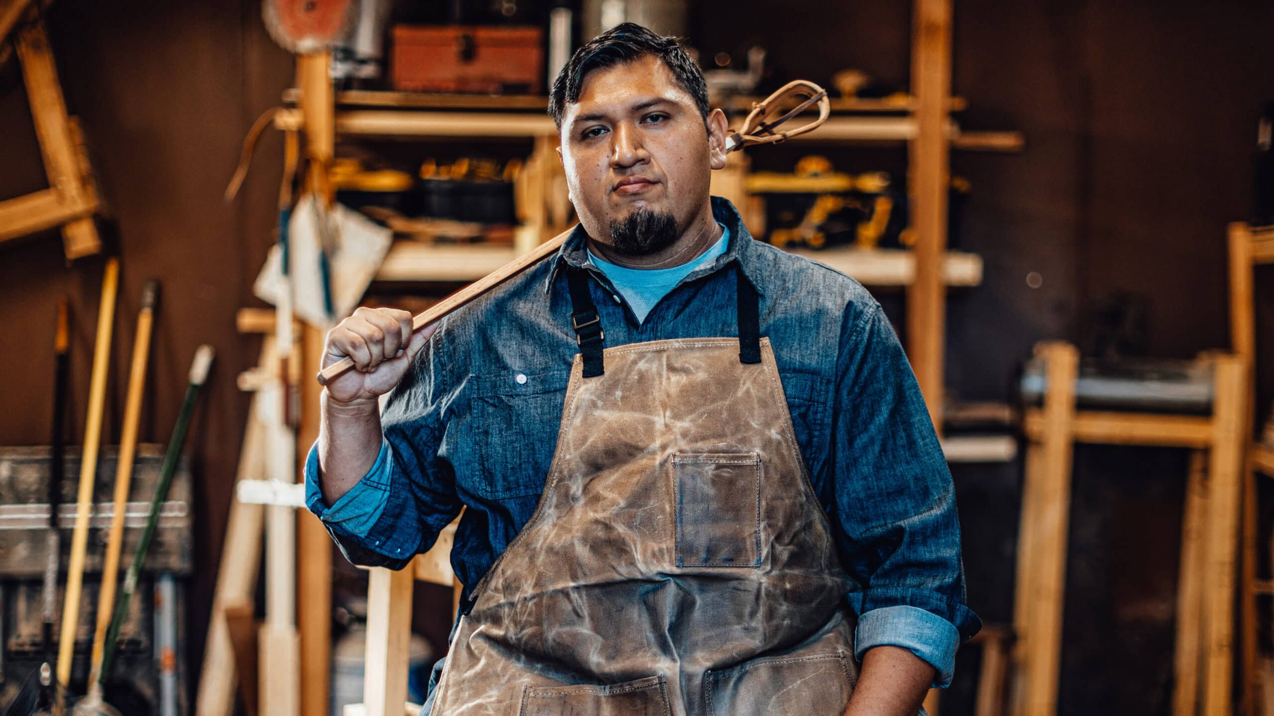 Brenner Billy poses in front of his workshop holding a stickball stick