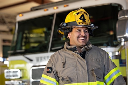Jake Trujillo smiles in front of a fire truck