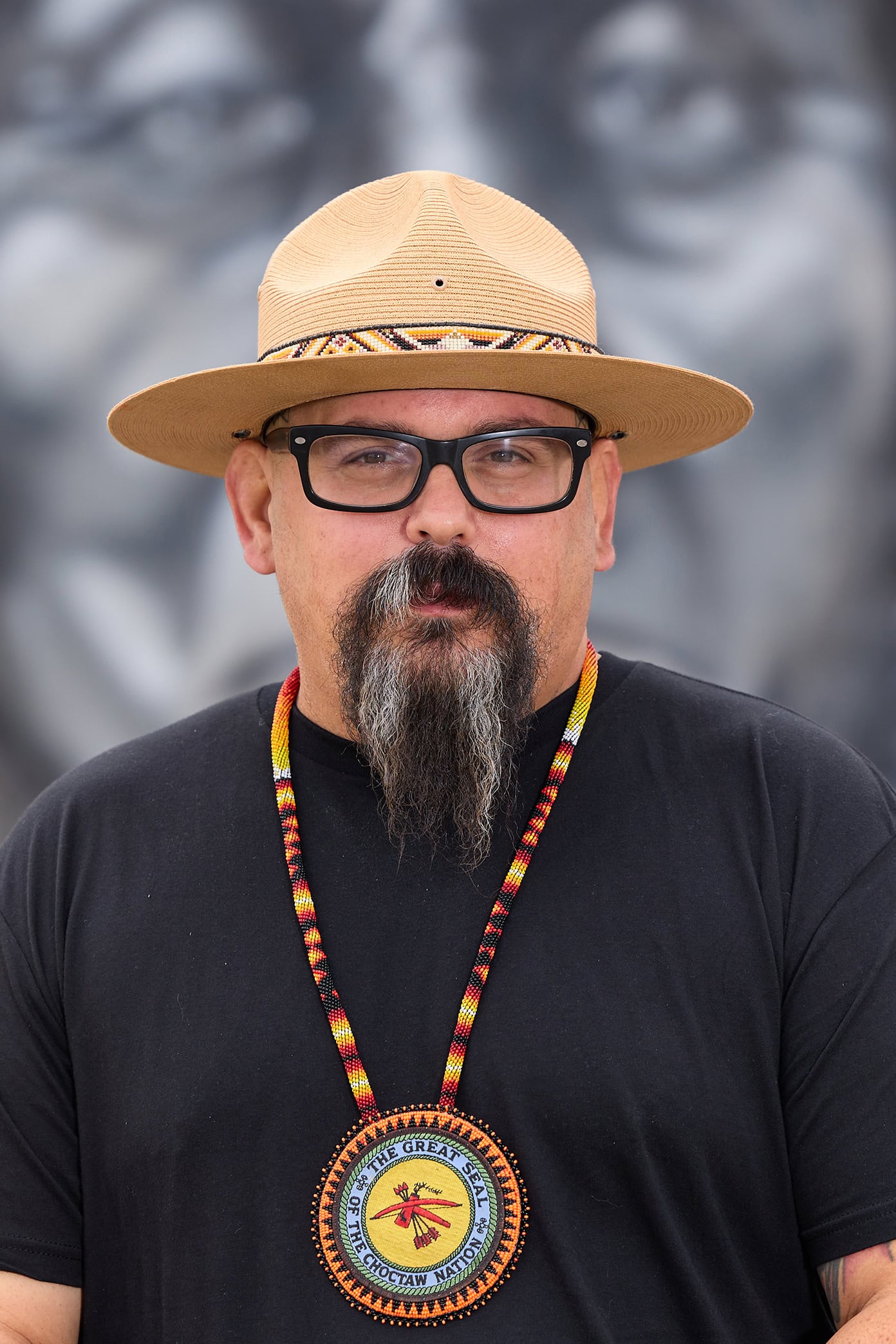 Bobby Von Martin wearing a hat and a necklace with the seal of the Choctaw Nation of Oklahoma