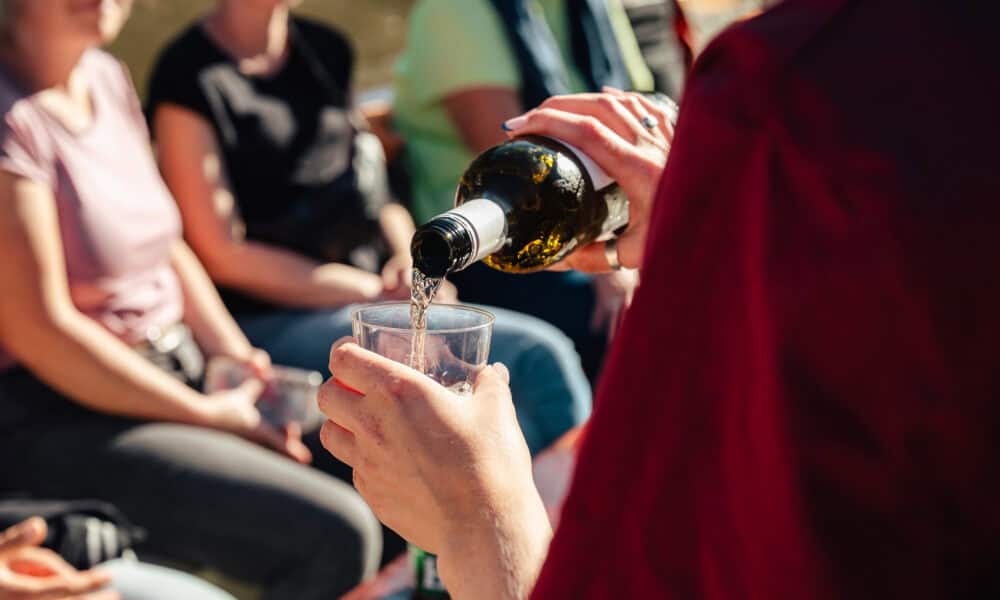person pouring wine into a glass, people sitting in background. A moment of relaxation in Amsterdam.