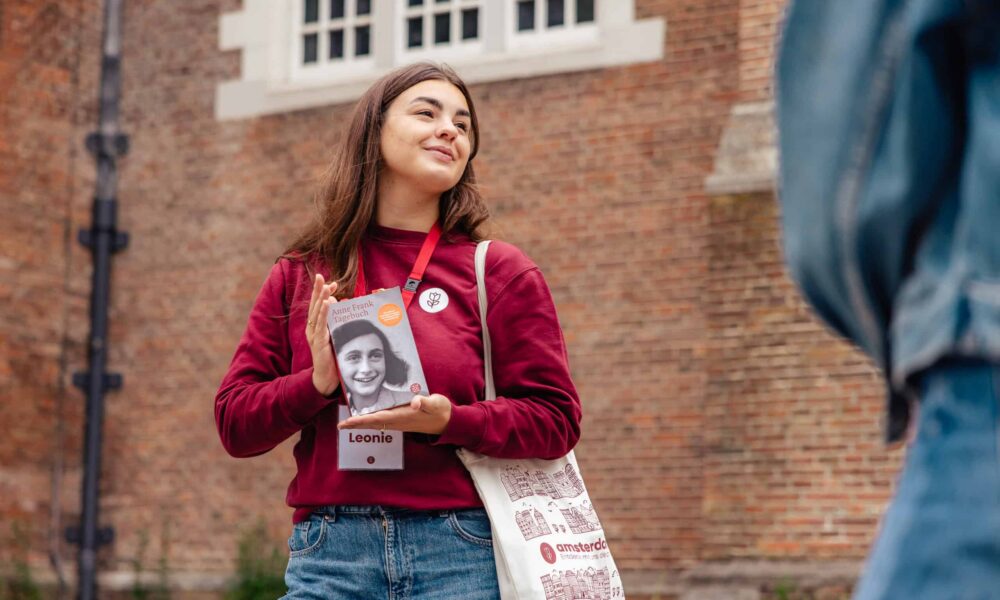 Leonie, a young tour guide from Amsterdamliebe, holding the Diary of Anne Frank during an Anne Frank Tour through Amsterdam