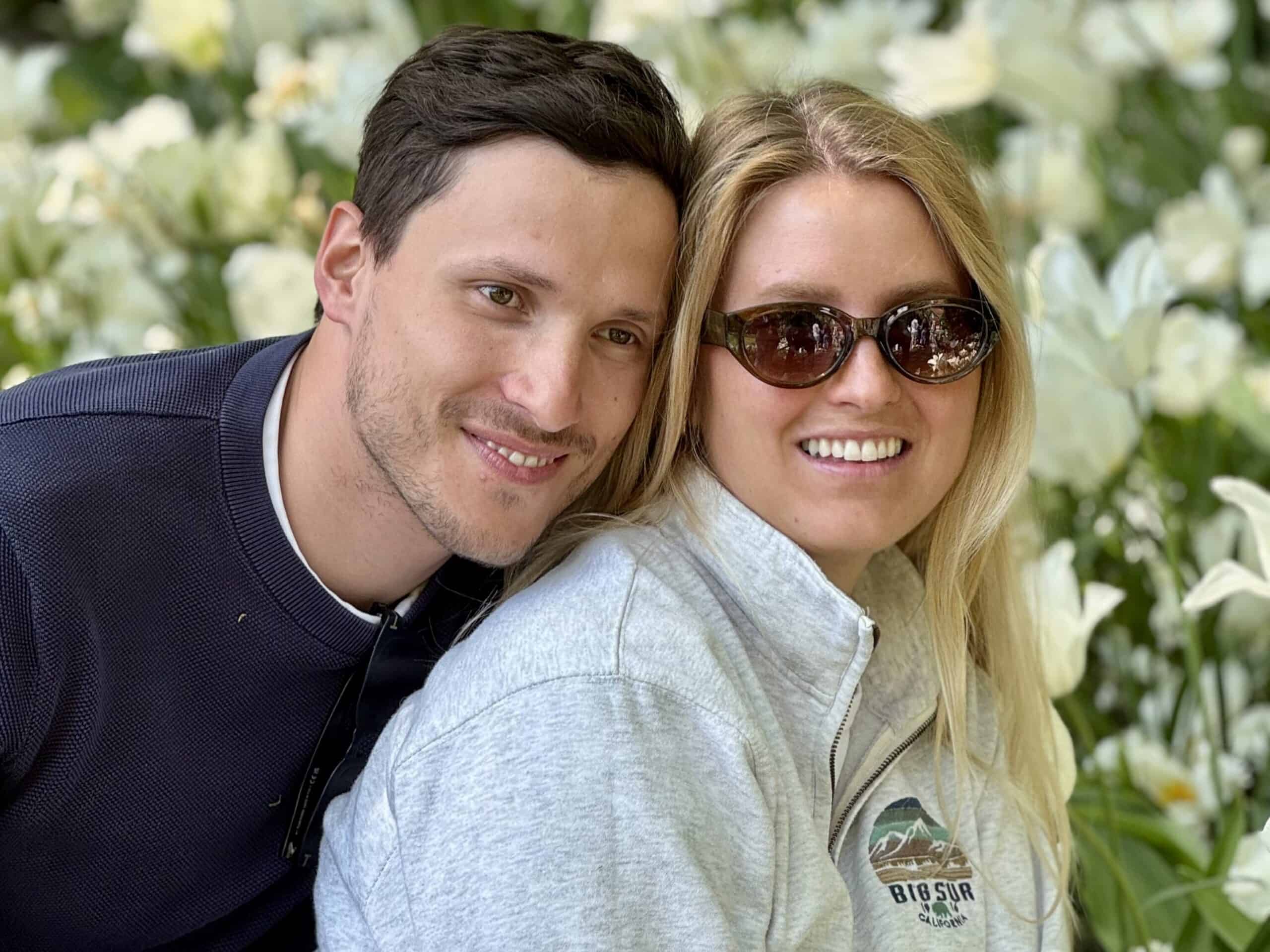 A man and woman embracing in a beautiful garden. They are smiling and enjoying each other's company.
