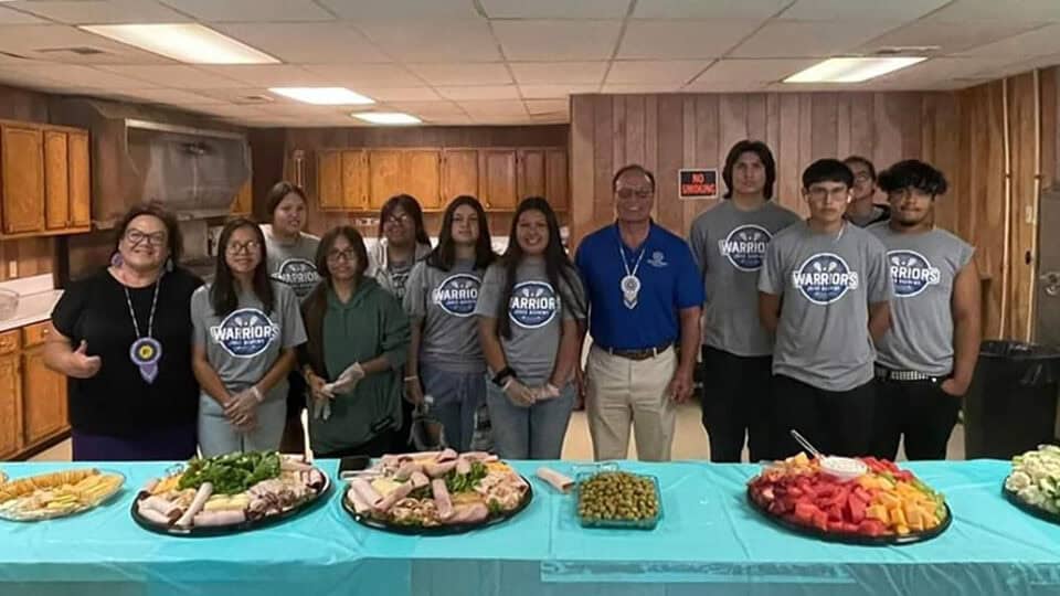 A group of Jones Academy students poses for a photo with Councilwoman Jennifer Woods and Chief Gary Batton behind a table full of food.