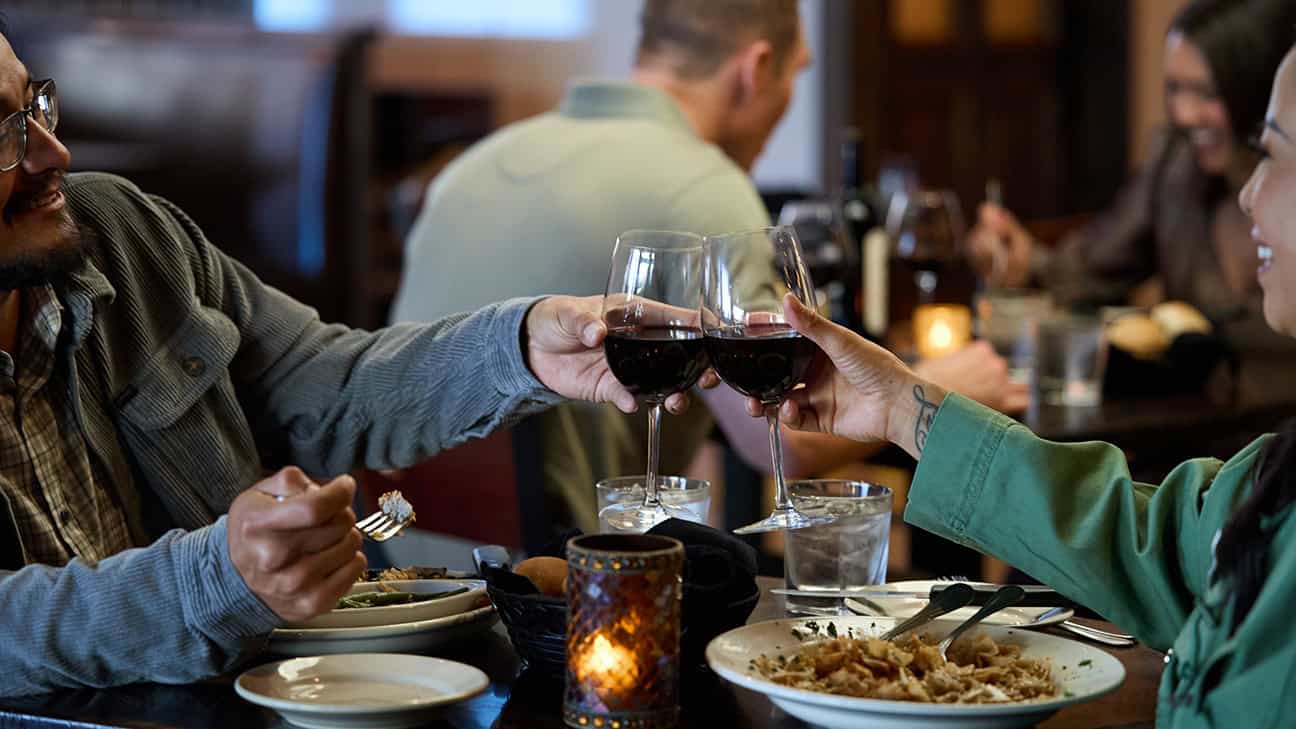 Two people toast with glasses of wine.