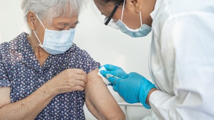 A doctor giving an elderly woman a shot in the arm.