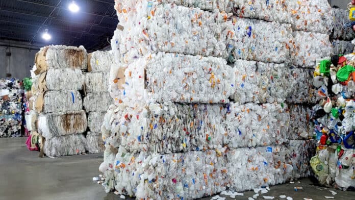 Bales of compressed plastic bottles and containers stacked in a recycling facility.