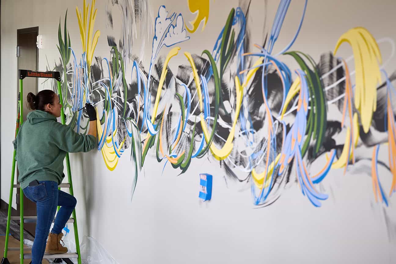 Rhiana Deck, muralist, actively worked on the mural in the front hallway of the clinic expansion during the ribbon cutting.