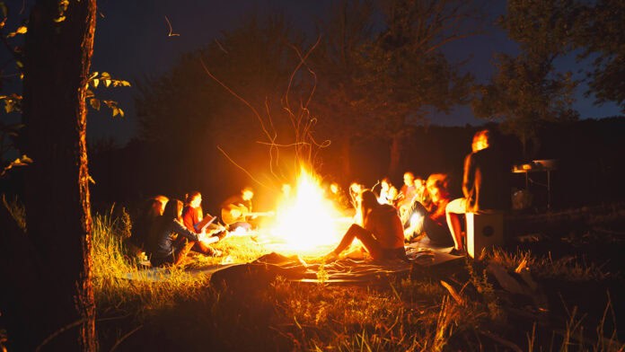 A group of people sitting around a campfire.
