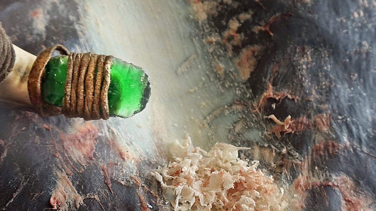 Glass scraper that has been used to thin a bison hide for tanning into a robe, showing the hide shavings removed.