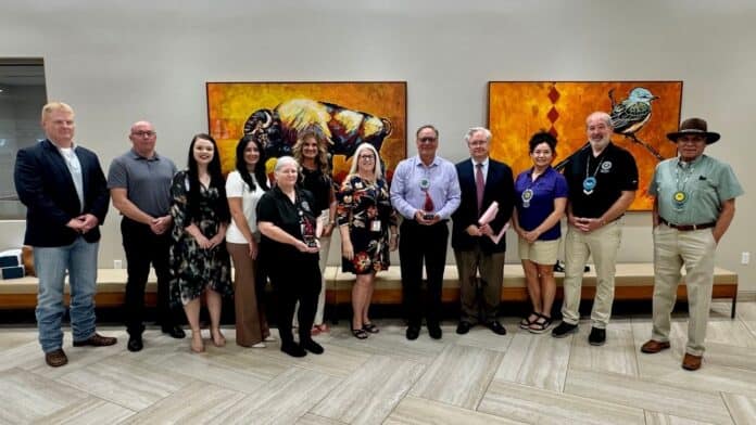 Representatives from OBI and Choctaw Nation blood drive champions pause with Chief Batton for a photo with the two awards.