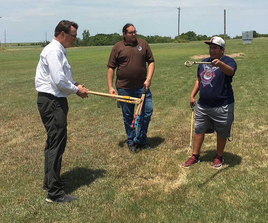 Jared Tom and Ryan Spring demonstrate stickball with Cultural Center Committee member Charles Mann