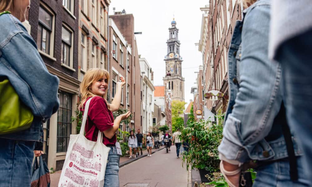 Tourists on a city trip in Amsterdam. A woman with a red shirt and a white bag.