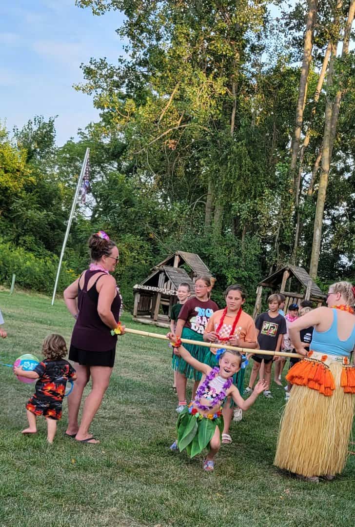 kids and adults doing the limbo outside dressed in luau gear