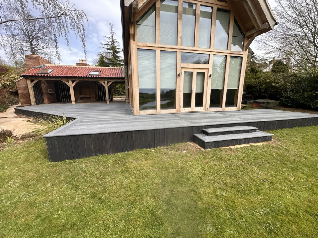 Charcoal Millboard deck and steps running the width of an oak framed house