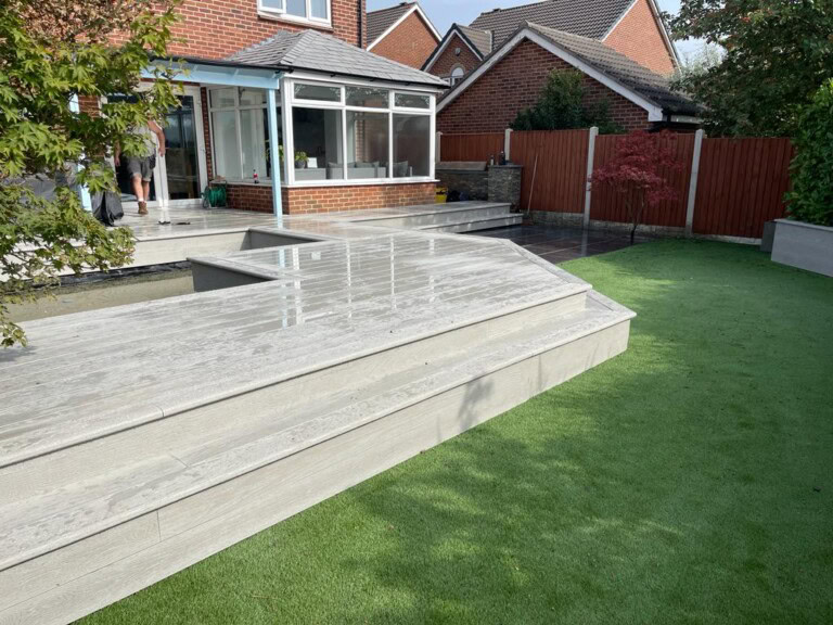 Grey Millboard deck with built in bench seating beside a pond