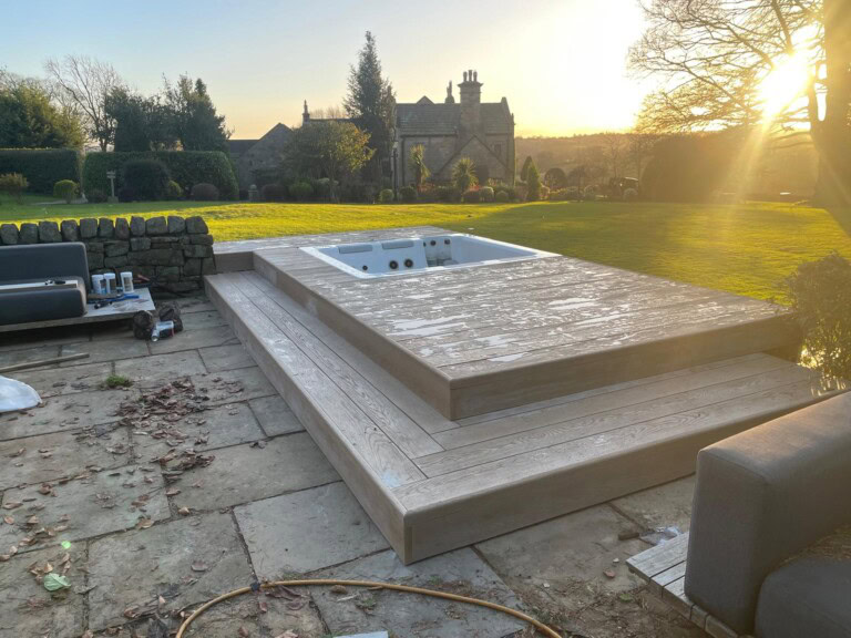 Millboard decking around a sunken hot tub at sunset