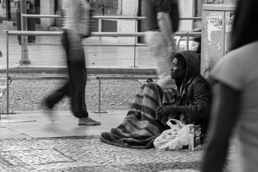 Texas homelessness crisis photograph of a homeless man on the city sidewalk as people rush past black and white photo