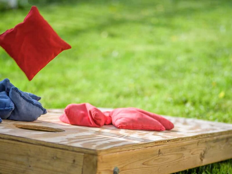A cornhole bag flies through the air towards the board.