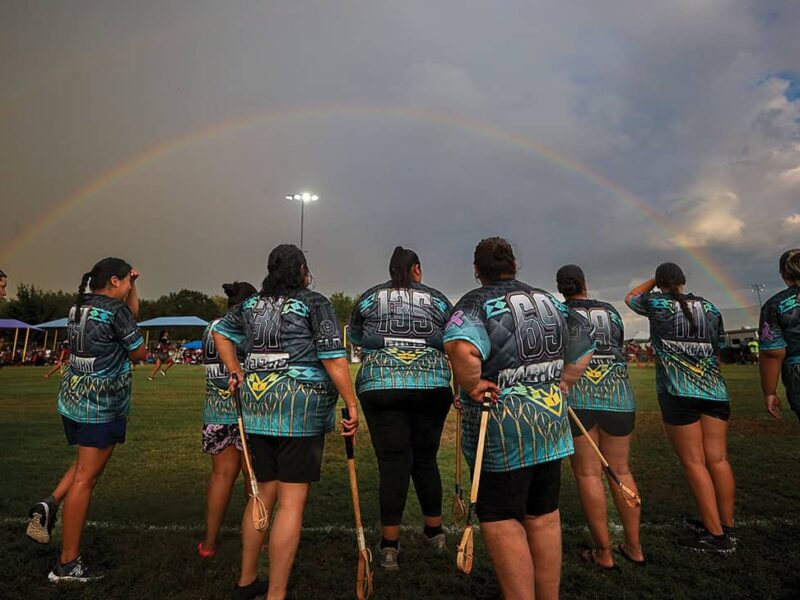 Players from Rogue stickball team watch their teammates compete after a rain shower.