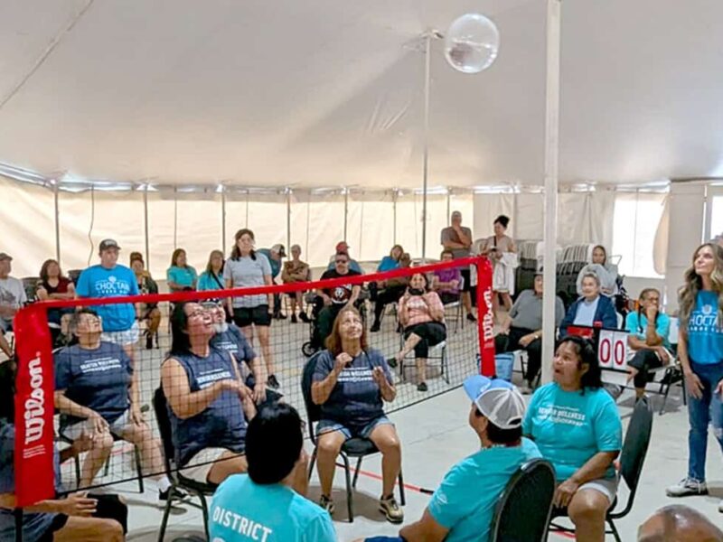 A group of elders play chair volleyball.