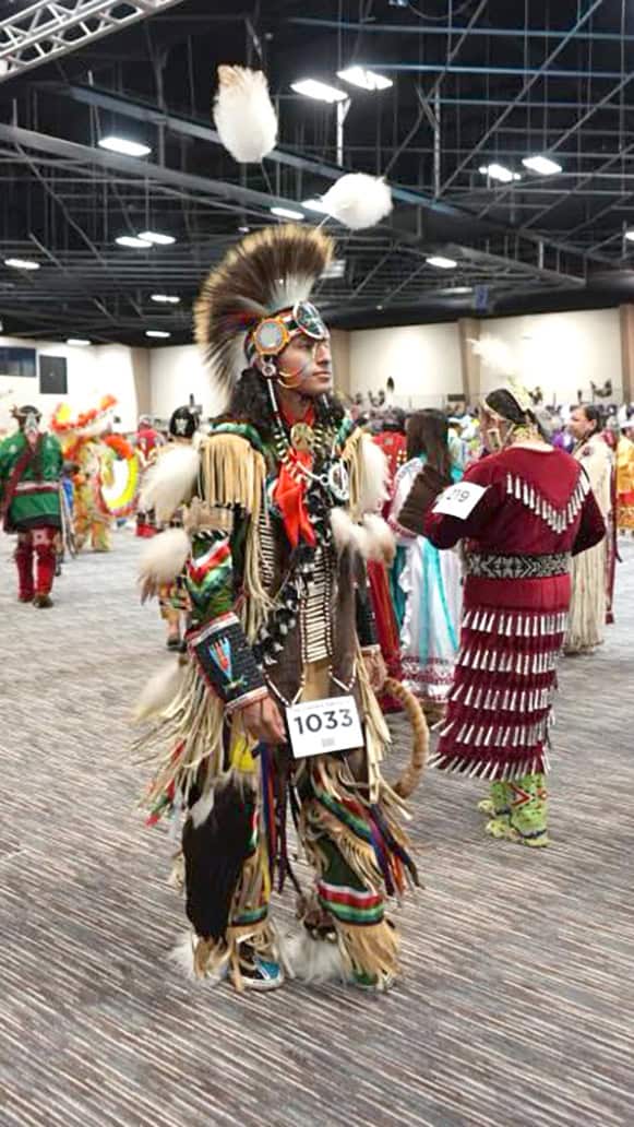 Powwow dancer walk through event center.