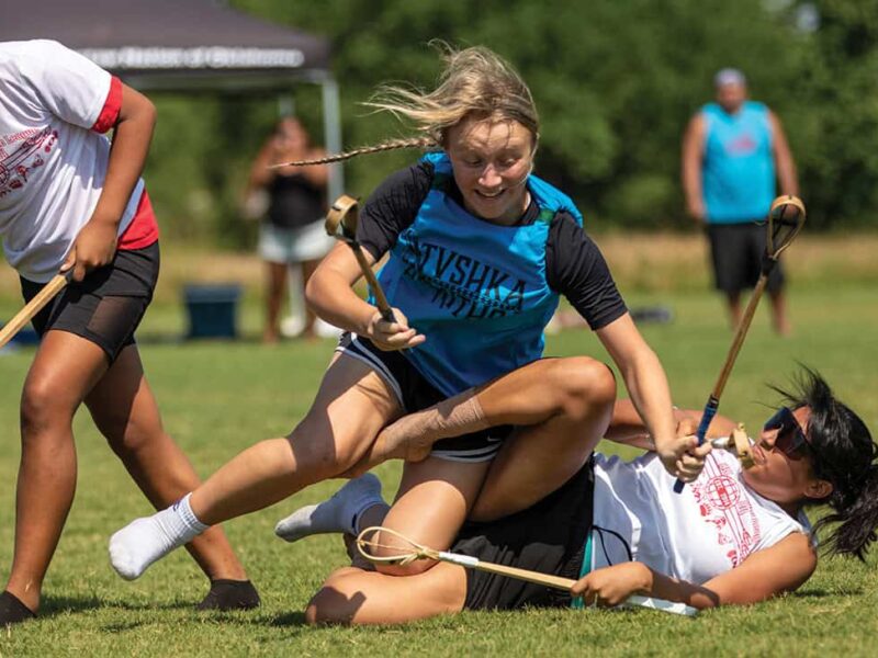 A women tackles another women during a game of stickball.
