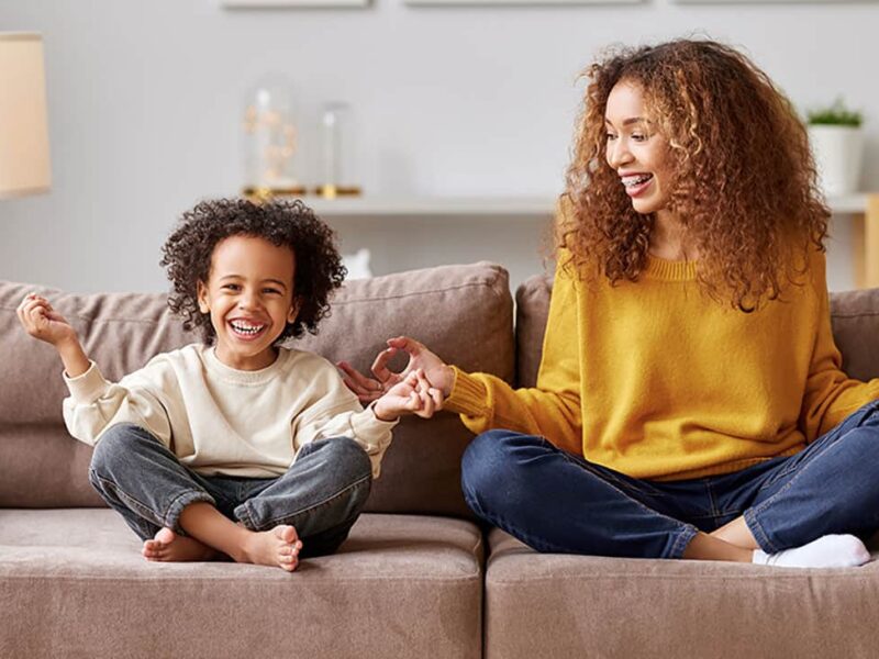Mother and son have fun practicing meditation on couch.