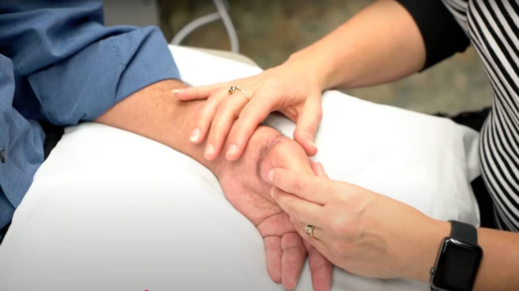 A physical therapist exercises a patients hand.