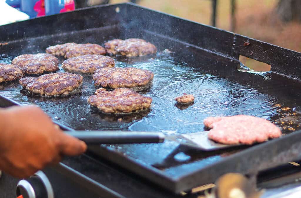 Hamburgers being cooked on an open grill.