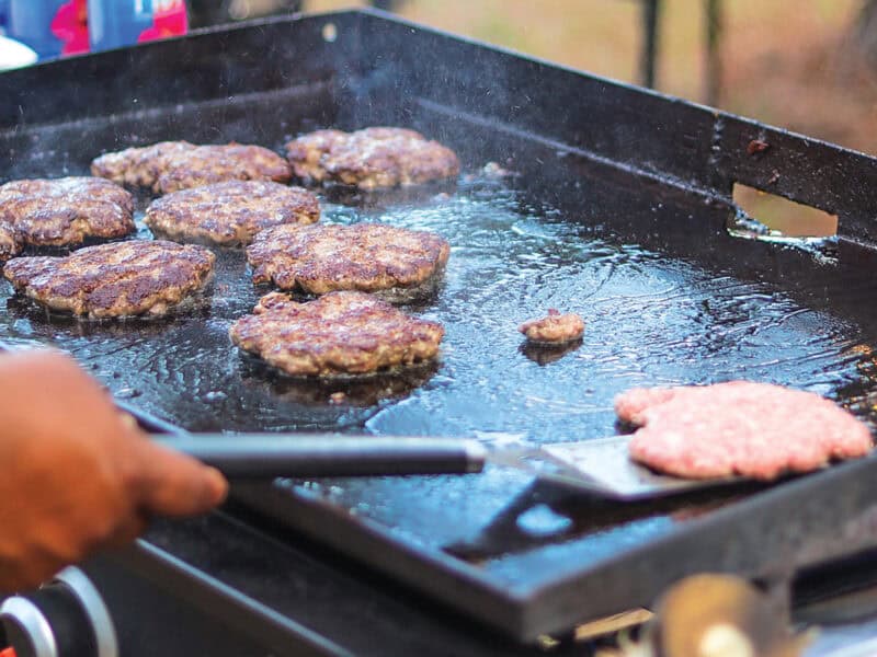 Hamburgers being cooked on an open grill.
