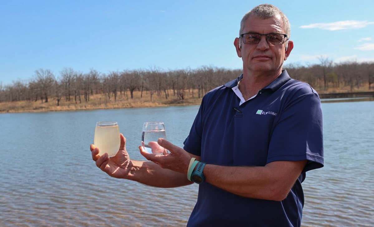 Man hold murky glass of water next to a crystal clear glass of water.