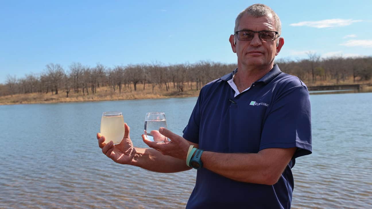 Man hold murky glass of water next to a crystal clear glass of water.