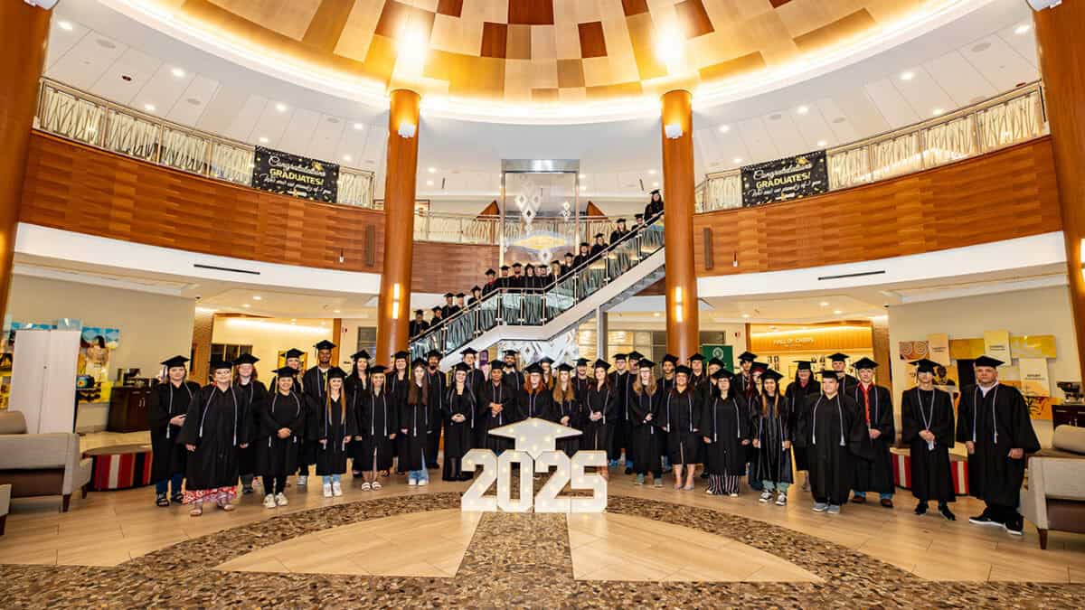 A large group of people pose for a photo wearing graduation caps and gowns.